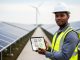 “Renewable energy professional holding a tablet with generic certification icons on a solar farm, with wind turbines in the blurred background.”